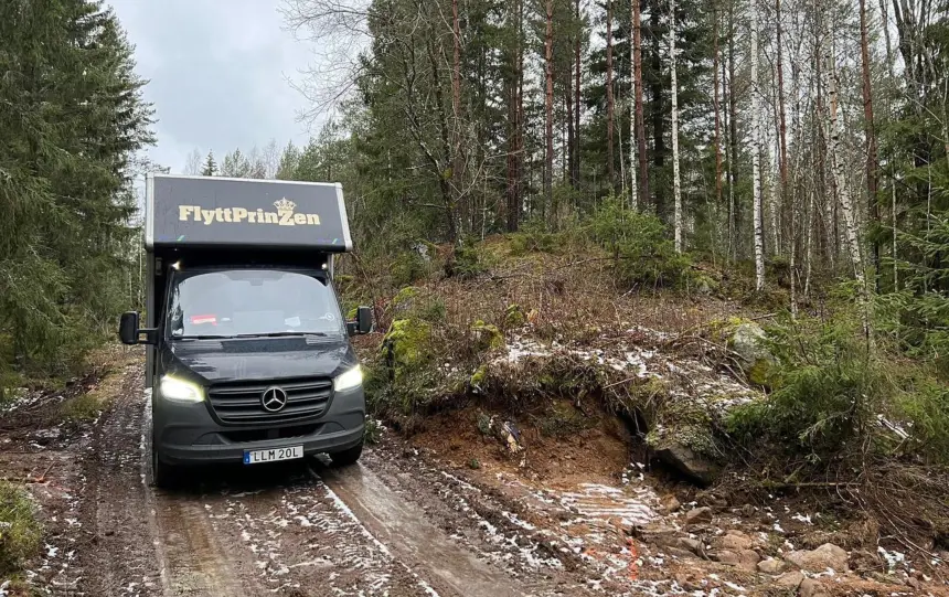 En svart lastbil som används vid flytt på en skogsväg.